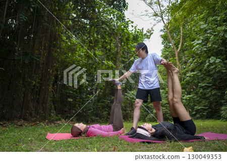 Indonesian southeast asian women in a sporty outfit practice exercise on a mat with a personal trainer man in a public park outdoors. Concept of a Healthy active lifestyle Indonesian southeast asian women in a sporty outfit practice exercise on a mat with a personal trainer man in a public park outdoors. Concept of a Healthy active lifestyle 130049353
