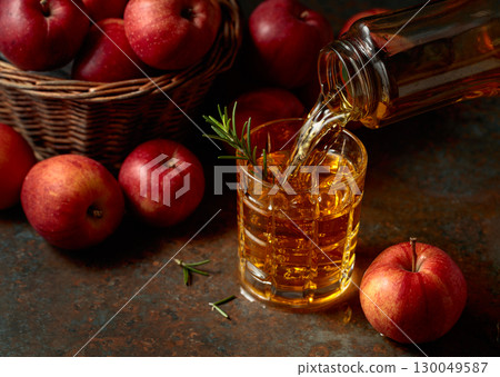 Apple kombucha is poured from a bottle into a glass. 130049587