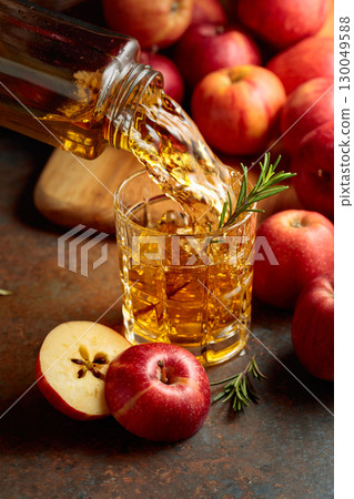 Apple juice is poured from a bottle into a glass. 130049588