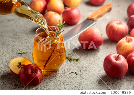 Apple cider is poured from a bottle into a glass. 130049589