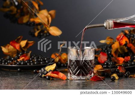 Black chokeberry juice and fresh berries on a black background. Black chokeberry juice and fresh berries on a black background. 130049600