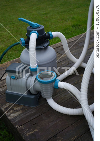 A pump with a filter for a private pool that stands outside on a sunny warm summer day. 130050276
