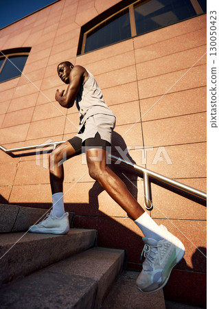 Athletic man engaged in outdoor stair workout on a sunny day Athletic man engaged in outdoor stair workout on a sunny day 130050423