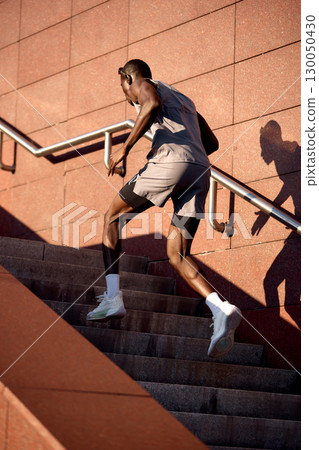 Athlete running upstairs outdoors during a sunny day in a fitness routine Athlete running upstairs outdoors during a sunny day in a fitness routine 130050430
