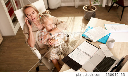 Mother balancing work responsibilities while caring for her young child at home Mother balancing work responsibilities while caring for her young child at home 130050433
