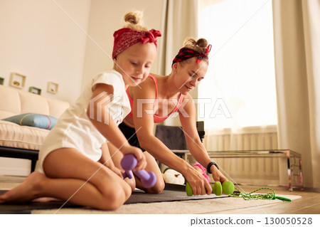 Mother and daughter preparing workout equipment in living room for exercise 130050528