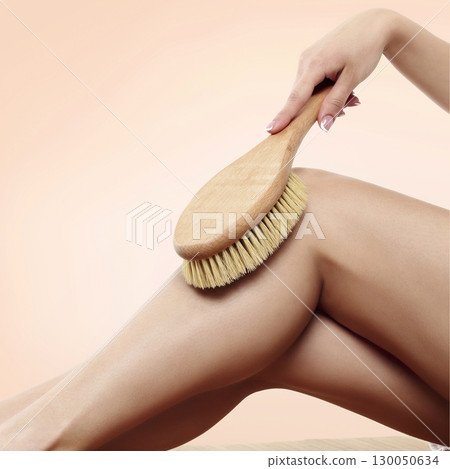 Woman is massaging skin on her legs with big brush Woman is massaging skin on her legs with big brush 130050634