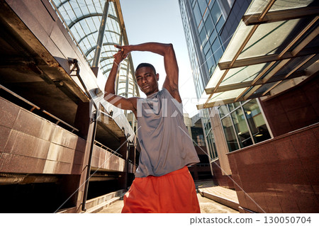 Man stretching outdoors in an urban area before exercise under clear skies Man stretching outdoors in an urban area before exercise under clear skies 130050704