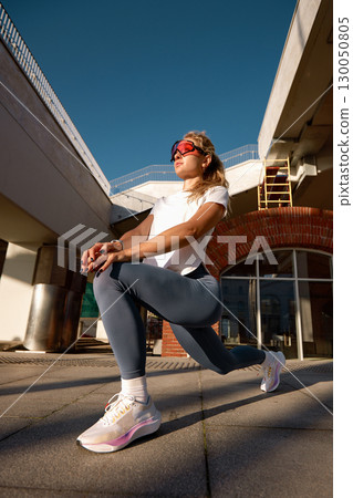 Young woman performing a stretching exercise outdoors under a clear sky Young woman performing a stretching exercise outdoors under a clear sky 130050805
