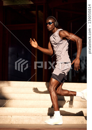 Fitness enthusiast running during workout in urban outdoor environment 130050814