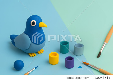 playful arts and crafts set up on a split mint and blue background. Clay Creation pigeon, small paint pots. Creative art and childhood craft concept 130051314