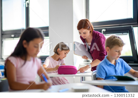 Teacher talking with children in primary class. Teacher talking with children in primary class. 130051332