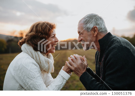 Senior couple holding hands in autumn sunset light. 130051376