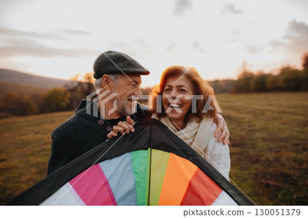 Senior couple flying a kite during warm autumn evening. 130051379