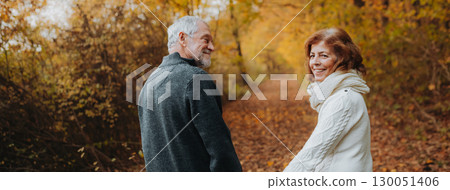 Retired couple standing in the middle of colorful autumn woods. Retired couple standing in the middle of colorful autumn woods. 130051406