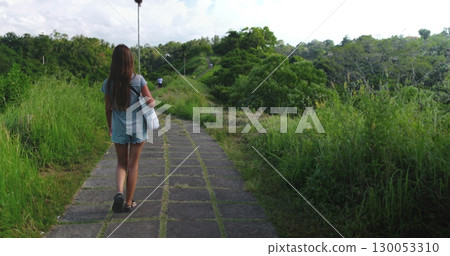 Woman walks through lush rice fields in ubud, bali, enjoying the peaceful landscape. She explores nature, feeling free and adventurous in southeast asia 130053310
