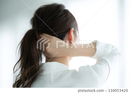 Woman holding the back of her head 130053420