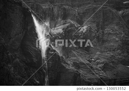 Flowing waterfall cascading down rugged cliffs of Cirque de Gavarnie in the Pyrenees, showcasing 130053552