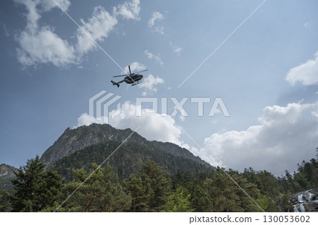 Helicopter conducting police operations in Cauteret, Pyrenees near Gavarnie under overcast skies 130053602