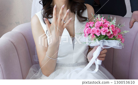 The bride shows the ring on his finger and smiles. a bouquet of flowers 130053610