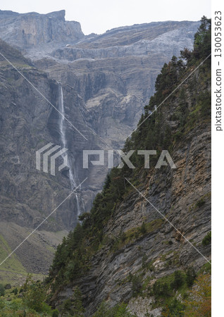 Flowing waterfall cascading down rugged cliffs of Cirque de Gavarnie in the Pyrenees, showcasing 130053623