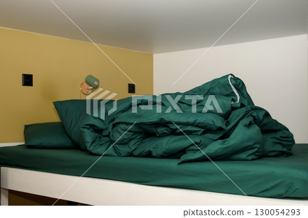 a bunk bed with a green, crumpled, and messy blanket. a simple and a cozy design. messy bunk bed cozy room. crumpled green blanket lazy morning 130054293