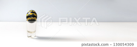 banner with a traditional pysanka, Ukrainian Easter egg, against a clean white background. Ukrainian folk art holiday template. black and yellow Easter egg design. pysanka Ukrainian Easter egg banner 130054309