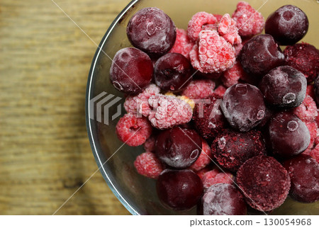 Bunch Of Whole Defrosted Red Berries In A Glass Bowl On Wooden Surface Bunch Of Whole Defrosted Red Berries In A Glass Bowl On Wooden Surface 130054968