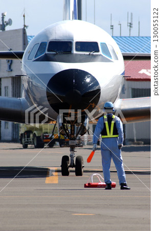 Ground staff signaling an arriving propeller plane 130055122