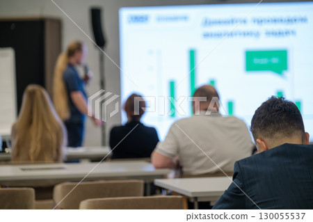 Audience listening to business presentation displayed on a graph board Audience listening to business presentation displayed on a graph board 130055537