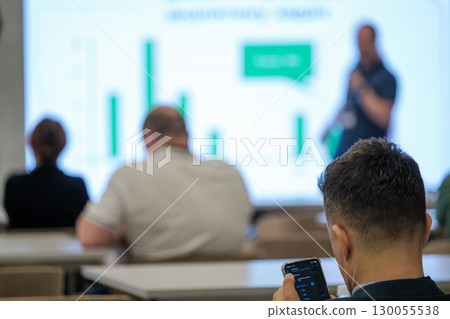 Man using smartphone during presentation with blurry background in conference room Man using smartphone during presentation with blurry background in conference room 130055538