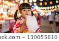 在日本夏季節日上，一個穿著浴衣的可愛小女孩正在吃棉花糖 130055610