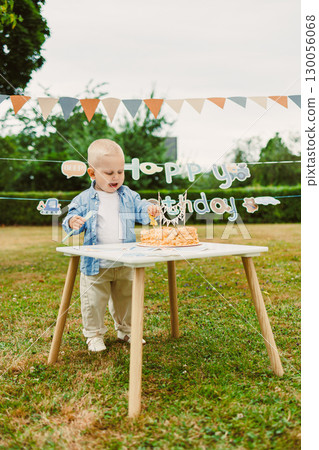 A young child joyfully celebrates their birthday outdoors with a cake adorned with candles and colorful bunting, creating a cheerful atmosphere filled with laughter and lasting memories A young child joyfully celebrates their birthday outdoors with a cake adorned with candles and colorful bunting, creating a cheerful atmosphere filled with laughter and lasting memories 130056068