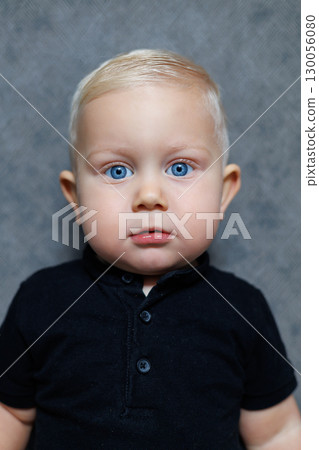 This truly adorable toddler, with captivating and beautiful blue eyes, is wearing a stylish black shirt that perfectly highlights their cheerful and lively personality in this enchanting portrait 130056080