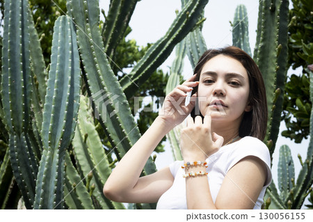 Beautiful woman standing in front of a cactus Beautiful woman standing in front of a cactus 130056155