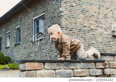 A curious toddler is exploring the great outdoors with an infectious sense of playful curiosity, discovering all the wonders that nature has to offer during this beautiful autumn season 130056182