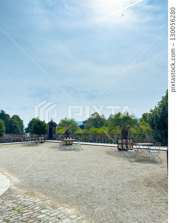 A Serene Outdoor Courtyard featuring beautiful Cobblestone Pathways and Lush Green Trees, all under a Clear Blue Sky, creating an idyllic atmosphere for relaxation and leisure in nature 130056280