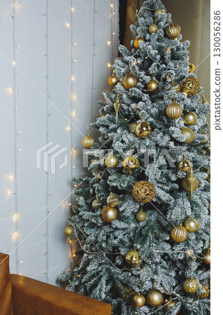 Experience a festive ambiance with a snowfrosted Christmas tree decorated with gold ornaments, creating a warm backdrop that enhances the spirit of celebration and togetherness this season 130056286