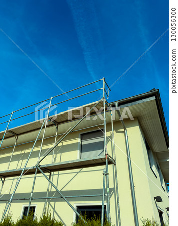 A sturdy scaffold has been successfully installed for a comprehensive home renovation project, all set under a vibrant and clear blue sky, ensuring the best conditions for quality work 130056300