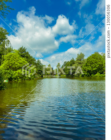 Tranquil Reflections A Scenic View of a Serene Lake, Visibly Surrounded by Lush Greenery and Soft Clear Blue Skies That Create an Idyllic Atmosphere for Relaxation and Reflection on Natures Beauty Tranquil Reflections A Scenic View of a Serene Lake, Visibly Surrounded by Lush Greenery and Soft Clear Blue Skies That Create an Idyllic Atmosphere for Relaxation and Reflection on Natures Beauty 130056306