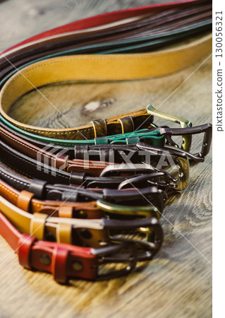 A stunning collection of fashionable and stylish leather belts elegantly displayed against a beautifully crafted wooden background that adds warmth and texture to the presentation 130056321