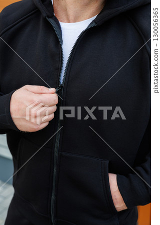 This is a detailed closeup view of a casual black hoodie featuring a zipper and a hood, showcased on a stylish model. It exemplifies contemporary sportswear, perfect for everyday lifestyle looks This is a detailed closeup view of a casual black hoodie featuring a zipper and a hood, showcased on a stylish model. It exemplifies contemporary sportswear, perfect for everyday lifestyle looks 130056365
