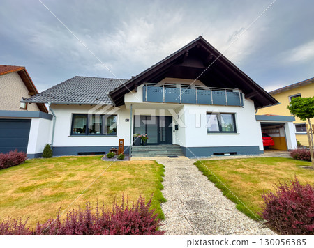 Discover a charming modern house that features a cozy front lawn and showcases an elegant design, perfectly situated in a peaceful suburban neighborhood for a serene living experience 130056385