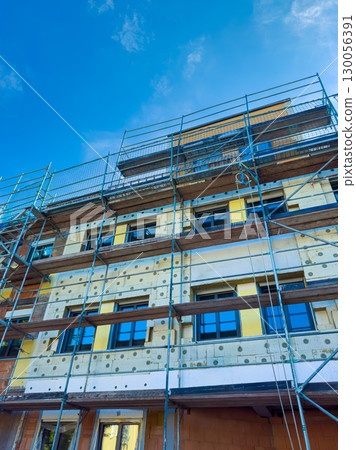 A modern building is currently under construction, featuring scaffolding that supports its structure against a stunningly clear blue sky, highlighting the ongoing urban development efforts 130056391