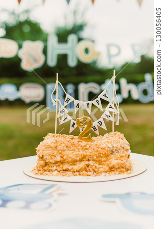 A beautifully crafted birthday cake adorned with a cheerful Happy Birthday banner, intended for a joyful outdoor celebration in honor of a toddlers second birthday party full of fun and laughter 130056405