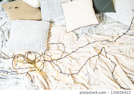 Create a cozy bedroom with cushions and string lights on soft textiles for a serene atmosphere. This stylish space embodies warmth, rustic charm, and a minimalist design for relaxation 130056422