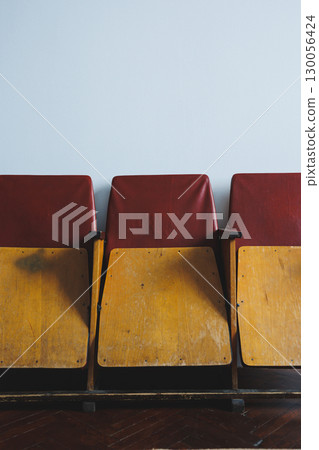 These Vintage Wooden Theater Chairs, featuring elegant Red Upholstery, are set against a chic Minimalist Wall, creating a stunning visual that enhances both aesthetic appeal and cultural atmosphere 130056424