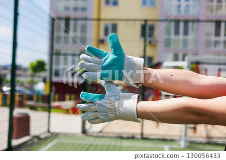 In outdoor settings, gloved hands symbolize safety and hygiene, reflecting the care in fitness and leisure activities, especially in playgrounds where teamwork and collaboration flourish In outdoor settings, gloved hands symbolize safety and hygiene, reflecting the care in fitness and leisure activities, especially in playgrounds where teamwork and collaboration flourish 130056433