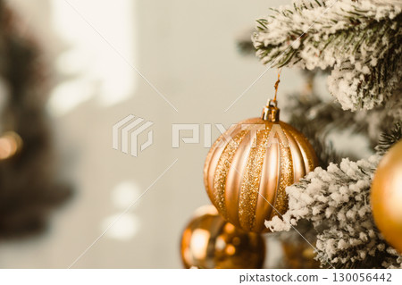 Elegant Golden Christmas Ornaments Adorning a Beautiful Winter Tree A Perfect Holiday Decoration to Enhance Your Festive Celebrations and Bring Cheer to Family Gatherings this Season 130056442