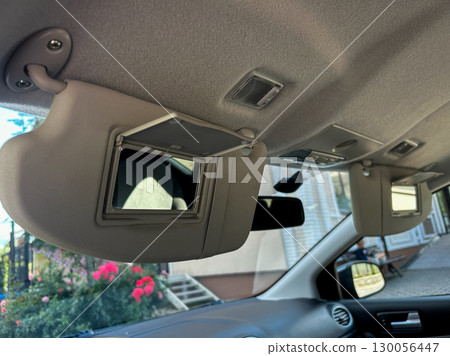 The image prominently features a cars sun visor that is equipped with a clear mirror, allowing for expansive views, which significantly enhances the travel experience for all passengers on board The image prominently features a cars sun visor that is equipped with a clear mirror, allowing for expansive views, which significantly enhances the travel experience for all passengers on board 130056447